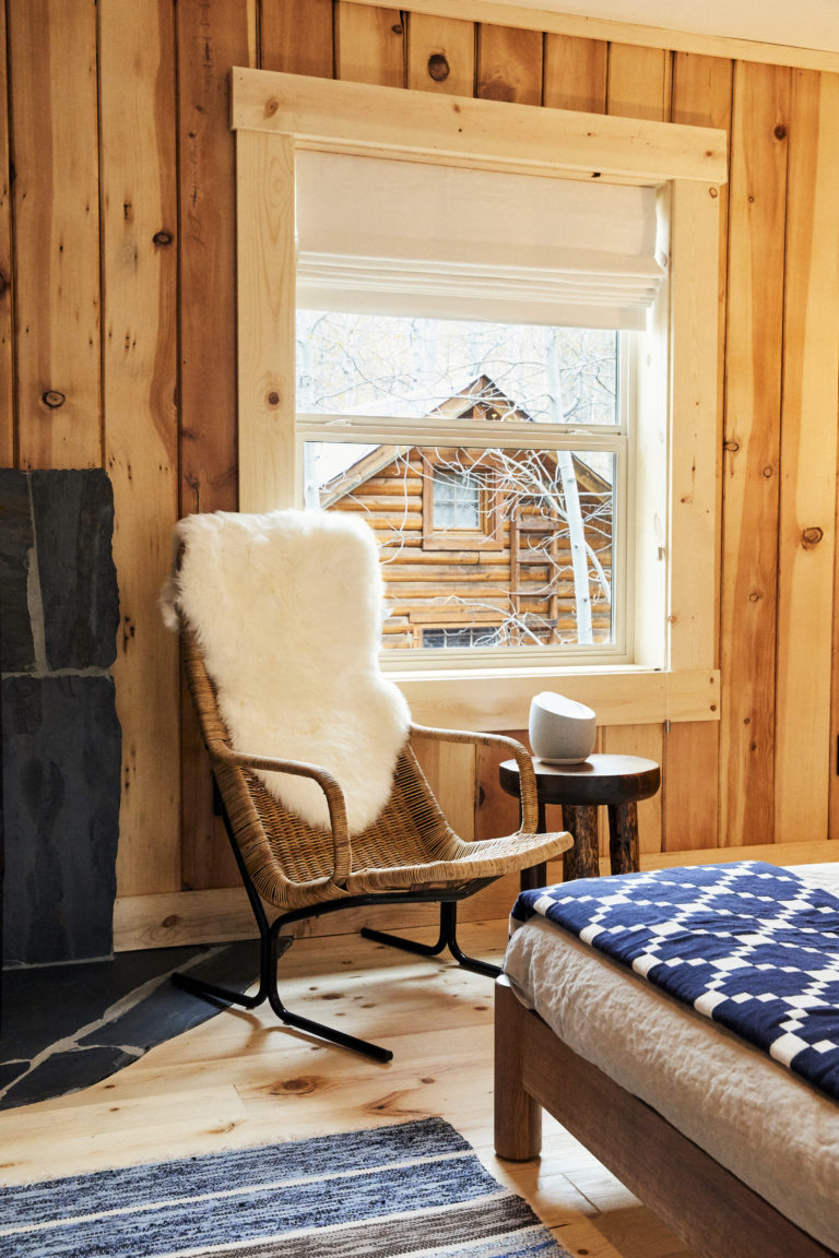 Guest chair with fur throw and window looking out at another cabin