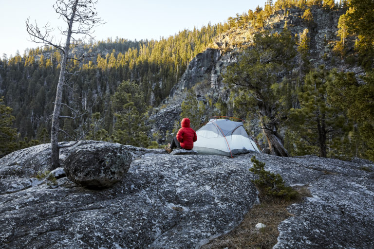 Camp site with guest sitting outside tent looking at nature