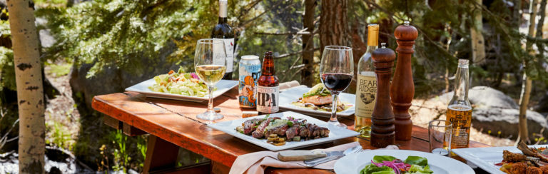 Picnic table with food set up and wine
