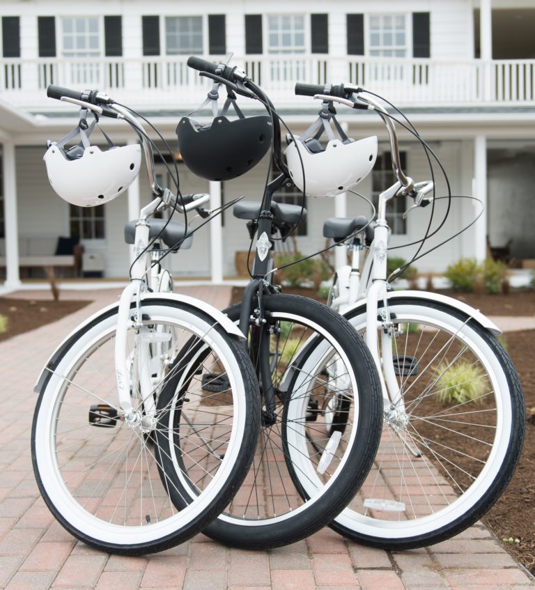 Three bikes parked with helmets hanging on the handels
